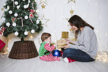 Eine Frau beschenkt einen kleinen Jungen, während sie an Weihnachten zu Hause sitzt - EBBF01715
