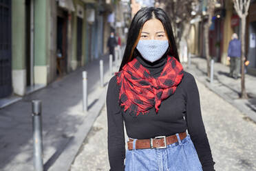 Junge Frau mit Gesichtsschutzmaske auf der Straße in der Stadt - VEGF03231