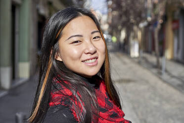 Woman smiling while standing on street in city - VEGF03232