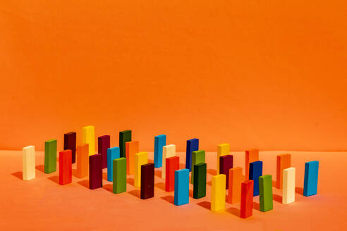 Anordnung von bunten Spielzeugblöcken in einer Reihe auf orangefarbenem Hintergrund - ERRF04746