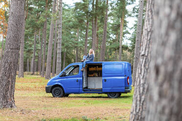 Mittlere erwachsene Frau sitzt auf dem Dach eines Wohnmobils in Cannock Chase - WPEF03766