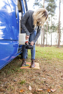 Blonde Frau füllt Wasser in eine Camping-Teekanne in Cannock Chase - WPEF03784