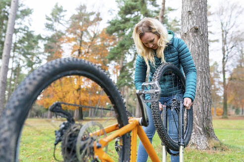 Blonde Frau repariert Fahrrad in Cannock Chase - WPEF03792