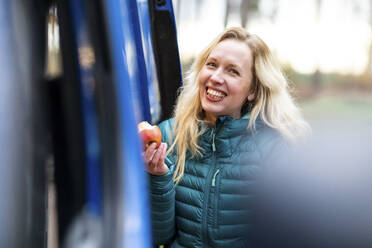 Blonde Frau mit Apfel am Wohnmobil - WPEF03798