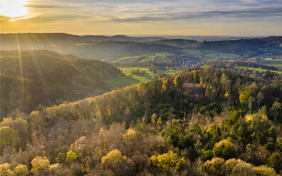 Drone Blick auf Herbst Wald bei Sonnenaufgang mit Dorf im Hintergrund - STSF02698