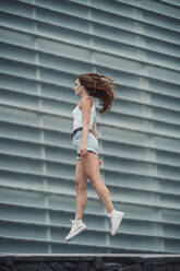 Young woman walking against wall - MTBF00739