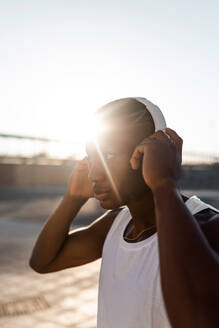 Porträt eines ernsthaften afroamerikanischen Läufers, der im Freien mit Kopfhörern Musik hört - ADSF18610