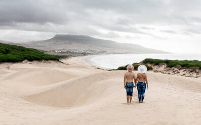 Zurück Blick in voller Länge romantische shirtless Paar trägt Jeans und Hüte halten die Hände, während die Ausgaben Sommer Tag zusammen auf sandigen Küste und bewundern Sie erstaunliche Aussicht - ADSF18736