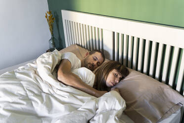 Mid adult couple sleeping together on bed at home - AFVF07703