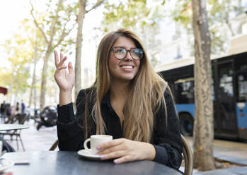 Lächelnde Frau mit Kaffee in einem Straßencafé in der Stadt - JCCMF00094