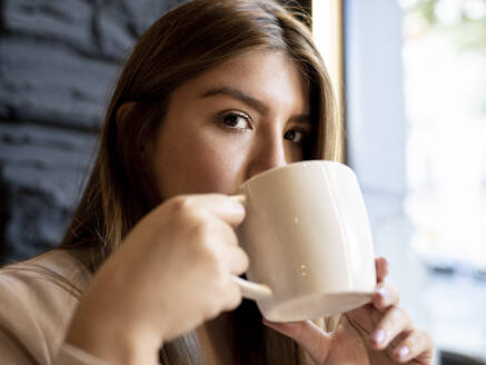Woman staring while drinking coffee at cafe - JCCMF00109