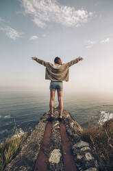 Young woman standing with arms outstretched against sky - MTBF00748