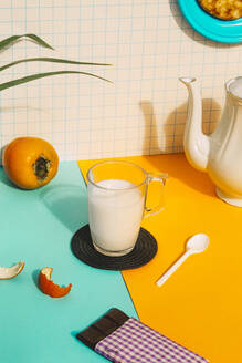 Milchtasse mit Schokolade und Teekanne auf buntem Tisch an der Wand - ERRF04788