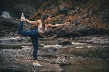 Sportler balanciert beim Yoga am Fluss im Wald im Ordesa-Nationalpark, Huesca, Spanien - ACPF00954