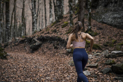 Junge Sportlerin, die im Herbst im Ordesa-Nationalpark im Wald läuft, Huesca, Spanien - ACPF00957