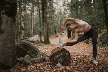 Young sportswoman stretching while standing in forest at Ordesa National Park, Huesca, Spain - ACPF00960