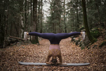 Sportswoman stretching while doing headstand in forest at Ordesa National Park, Huesca, Spain - ACPF00963