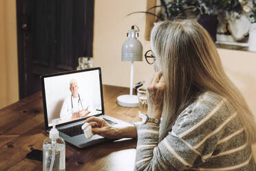 Senior patient taking advice of male doctor on video call during COVID-19 - ERRF04796