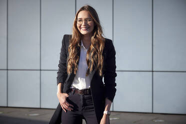 Female professional smiling while standing against wall - RHF02467