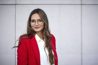 Geschäftsfrau mit Brille an der Wand stehend - RHF02470