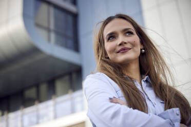 Thoughtful businesswoman looking away while standing outdoors - RHF02503