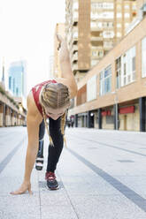 Sportler mit Beinprothese hockt beim Sportwettkampf auf dem Fußweg - IFRF00186