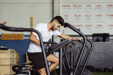 Junger Sportler trainiert auf einem Airbike im Fitnessstudio - MARF00010