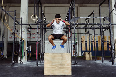 Junger Sportler bei der Ausübung von Boxsprüngen im Fitnessstudio - MARF00013