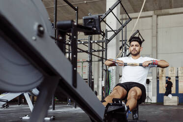 Sportler beim Training mit Rudergerät im Fitnessstudio - MARF00019