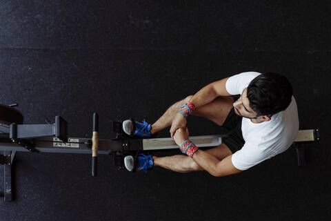 Athlete taking a break while sitting on rowing machine at gym stock photo