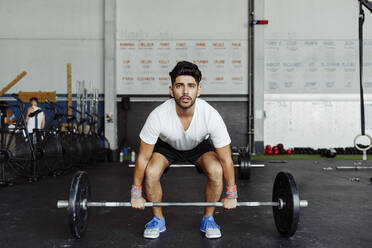 Junger Mann übt Gewichtheben im Fitnessstudio - MARF00023