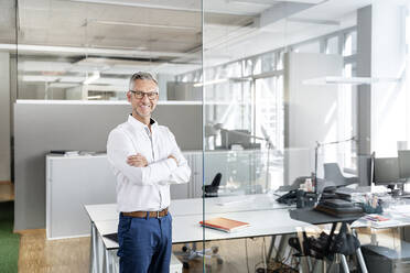 Smiling male professional with arms crossed in office - PESF02370