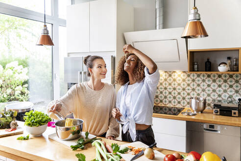 Businesswoman with colleague tasting spaghetti in office kitchen - PESF02400