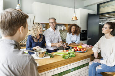 Lächelnde Geschäftskollegen unterhalten sich beim Kochen in der Büroküche - PESF02402