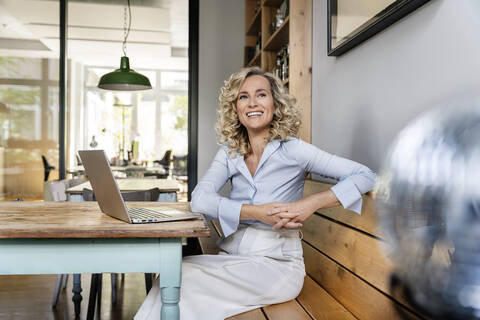 Glückliche weibliche Fachkraft mit Laptop träumt in der Büro-Cafeteria, lizenzfreies Stockfoto