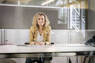 Reife Geschäftsfrau lächelnd am Schreibtisch im Büro - PESF02442