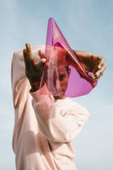 Man playing with pink plastic while standing against sky - AFVF07775