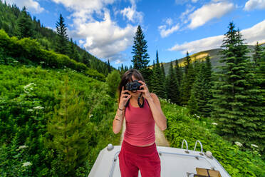 Frau mit Kamera auf dem Van-Dach, Bugaboo Property Released (PR)ovincial Park, British Columbia, Kanada - ISF24319
