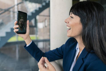 Lächelnde Geschäftsfrau bei einem Videogespräch mit einem männlichen Kollegen im Büro - JOSEF02509