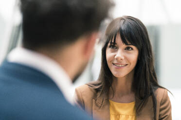 Smiling female entrepreneur looking at male colleague in office - JOSEF02510