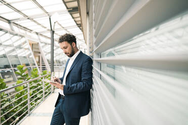 Männlicher Unternehmer mit digitalem Tablet an der Wand im Büro - JOSEF02535