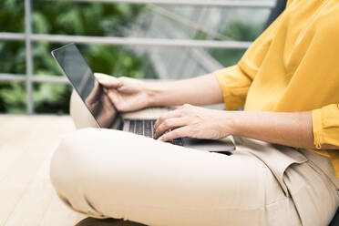 Businesswoman typing on laptop in office - JOSEF02609