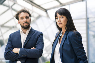 Male entrepreneur with arms crossed standing by confident female colleague - JOSEF02626