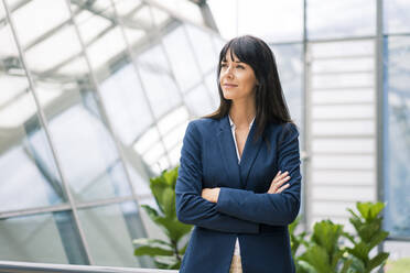 Thoughtful businesswoman with arms crossed looking away in office - JOSEF02631