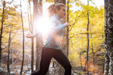 Young sportswoman practicing while running in forest - JSRF01256