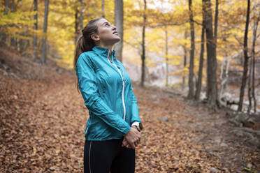 Sportlerin, die im Wald stehend nach oben schaut - JSRF01257