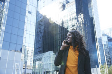 Lächelnde Unternehmerin bei einem Telefonat vor einem Bürogebäude - PMF01618
