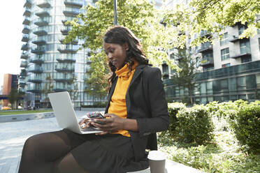 Berufstätige Frau mit Mobiltelefon und Laptop im Büropark - PMF01630