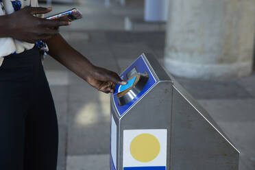 Geschäftsfrau scannt Fahrkarte am Automaten, während sie in der U-Bahn steht - PMF01684
