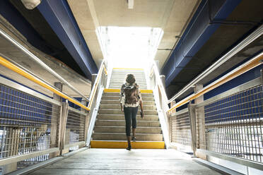 Businesswoman with backpack walking on steps in subway station - PMF01685